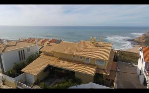 Elle offre une vue sur une maison et l'océan. dans l'établissement Sea House Apartment with Pool near Ericeira's great surf spots, à Ribamar