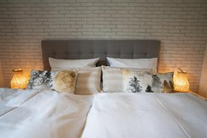 a white bed with pillows and a brick wall at Waldrausch Titisee in Titisee-Neustadt +7 photos