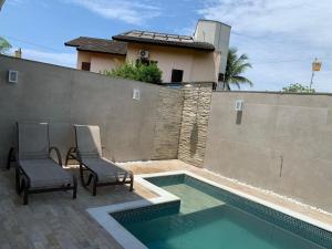 une piscine avec deux chaises à côté d'une maison dans l'établissement Casa em condomínio fechado, com piscina privativa em Juquehy, à São Sebastião