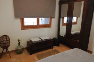 1 dormitorio con cama, espejo y silla en Ca l'Andròmines, en Pinell de Bray
