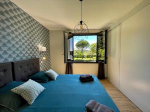 a bedroom with a blue bed and a window at L'écrin de la Cité, Coeur de Vignes in Carcassonne