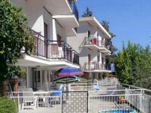a building with chairs and an umbrella in front of it at Residence La Carruba in Diano Marina