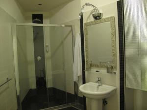 bagno con doccia, lavandino e specchio di Arches Inn a Roma