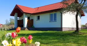 uma casa branca com um telhado vermelho e algumas flores em Wygodny Dom na Ponidziu z Basenem em Wiślica