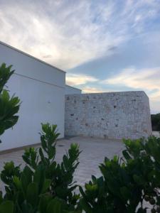 una pared de piedra junto a un edificio blanco en B&B CASA CALETA, en Porto Cesareo