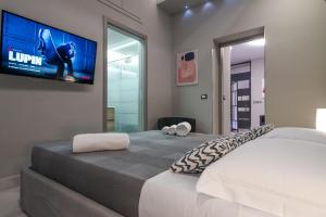 a bedroom with a bed with a flat screen tv on the wall at Suite Catania Lungomare in Catania