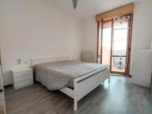 a white bedroom with a bed and a window at Finestra sul mare in Lido di Fermo