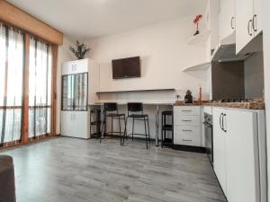 a kitchen with white cabinets and bar stools at Finestra sul mare in Lido di Fermo