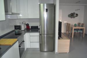 eine Küche mit einem Kühlschrank aus Edelstahl und einem Tisch in der Unterkunft Enjoy Denia in Denia