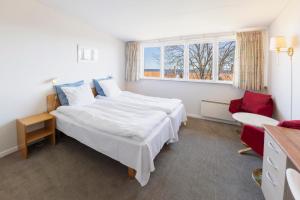 a bedroom with a large white bed and a window at Hotel Pepita in Allinge