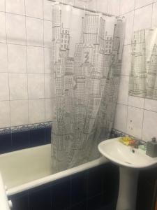 a shower curtain in a bathroom with a sink and a tub at ArArAt-HOLOSIIVSKYI Hostel KYIV in Kyiv