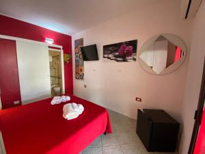 ein rotes Schlafzimmer mit einem roten Bett und einem Spiegel in der Unterkunft B&B Petite Maison in Posada