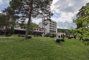 a large white building with a grass field in front of a building at Hotel Spa Cazino Monteoru in Sărata-Monteoru