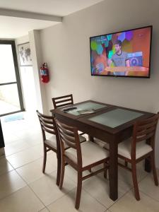 mesa de comedor con sillas y TV en la pared en Departamento Tranquilo en Tunuyán