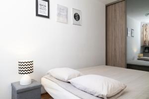 a white bedroom with a bed with white pillows at Własne M-Studio CENTRUM parter in Konin