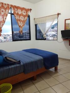 a bedroom with a bed and two windows at Taxco de mis amores in Taxco de Alarcón