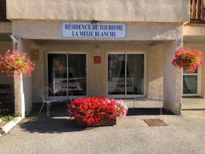 a building with two baskets of flowers in front of it at LA MEIJE BLANCHE "RESIDENCE DE TOURISME 2 étoiles" in Villar-dʼArène