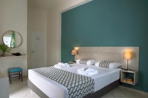 a bedroom with a large white bed with a blue wall at Bali Seaside Sailor in Balíon