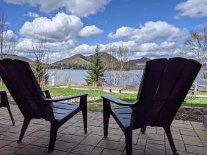 two chairs sitting on a patio with a view of a lake at Escapade Bonheur in Lac-Superieur