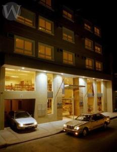 dos autos estacionados frente a un edificio por la noche en Wilson Hotel en Salta