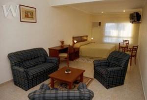 ein Wohnzimmer mit 2 Stühlen und einem Bett in der Unterkunft Wilson Hotel in Salta