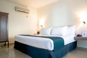 una camera d'albergo con un grande letto con cuscini bianchi di InHouse Culiacán a Culiacán