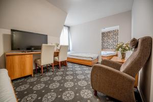 a living room with a television and a desk and chairs at City Hotel in Piešťany