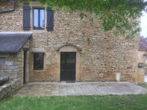 ein Steingebäude mit einer Tür und einem Fenster in der Unterkunft Maison 5 pièces dans hameau pittoresque très calme in Payrac