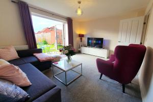 a living room with a couch and chairs and a tv at Meadow View, luxury home in heart of England in Shirebrook