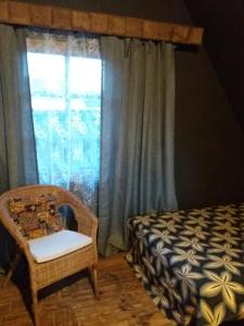 um quarto com uma cama, uma cadeira e uma janela em Namiņš em Vecumnieki