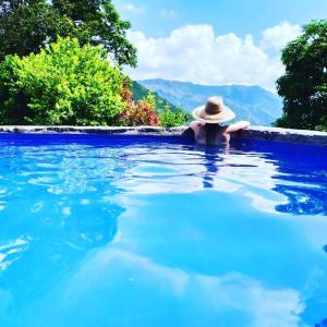 Una mujer con sombrero en una piscina en Hostal Payaca, en Bituima