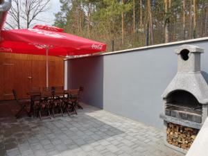 eine Terrasse mit einem Kamin und einem Tisch mit einem roten Regenschirm in der Unterkunft Ady Apartmanház in Orfű