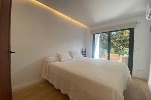 a white bedroom with a bed and a window at Beautiful designer home in Illetas in Illetas