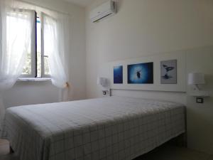 a white bedroom with a bed in a room with a window at Le Stelle di Orione in Fontane Bianche