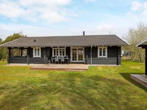 a black house with a porch and a patio at 6 person holiday home in R dby in Rødby