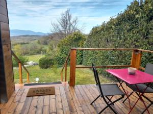 una terraza de madera con mesa y sillas rosas en Lodge avec vue panoramique, en Saint-Sorlin