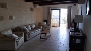 a living room with couches and a view of the ocean at Serena Flats, Serena Flat No 3, Triq Il-Fossilli Birzebbugia in Birżebbuġa
