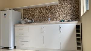 a kitchen with white cabinets and a white refrigerator at Casinhas da Vila - Itacaré in Itacaré