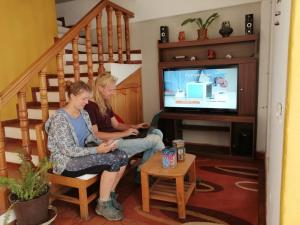 two women sitting on chairs in a living room watching tv at Pony's Lodge B&B in Caraz