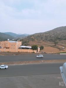 a white car driving down a road next to a building at جولدن السودة in Abha