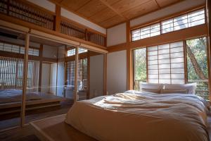 a bedroom with a large bed in a room with windows at プライベートリゾート 月灯 in Atami