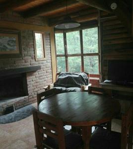 a living room with a table and a fireplace at Cabaña Atha Iti in Villa General Belgrano