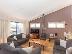 uma sala de estar com dois sofás e uma televisão em Acacia 5 2 Kirwan Close em Jindabyne