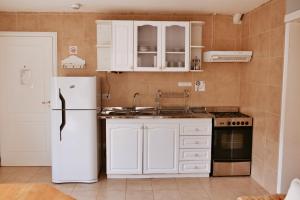 a kitchen with white cabinets and a white refrigerator at Aguila Mora Aparts in El Chalten