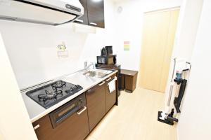 uma cozinha com um lavatório e um fogão forno superior em だるまマンション 902 em Naha