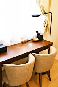 a wooden desk with two chairs and a lamp at だるまマンション 902 in Naha
