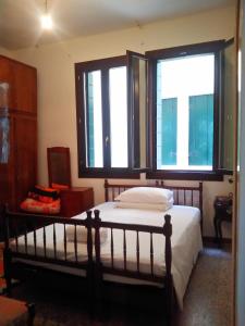 um quarto com uma cama e 2 janelas grandes em Cà Widmann em Veneza