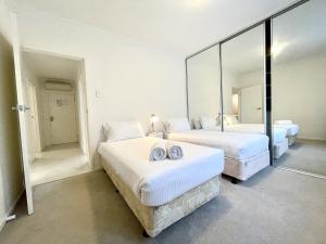 a bedroom with two beds and a large mirror at Brighton Villas by Readyset in Melbourne