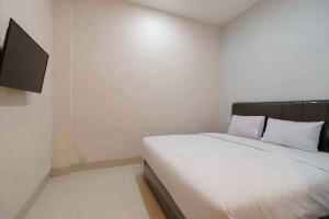 a bedroom with a bed and a flat screen tv at Seindo Hotel Mitra RedDoorz in Sunggal