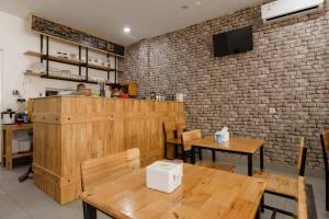 un restaurante con mesas de madera y una pared de ladrillo en Seindo Hotel Mitra RedDoorz en Sunggal